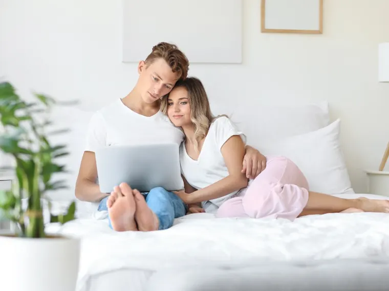 Casal com notebook e computador no quarto