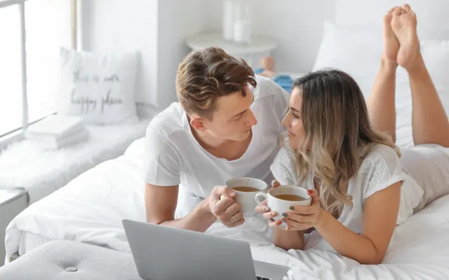 Casal com notebook e computador no quarto