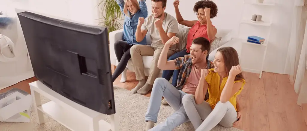 Família e amigos reunidos diante da TV na sala