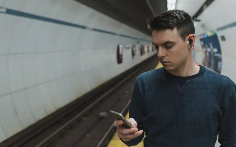 Homem com celular e fones de ouvido na cidade