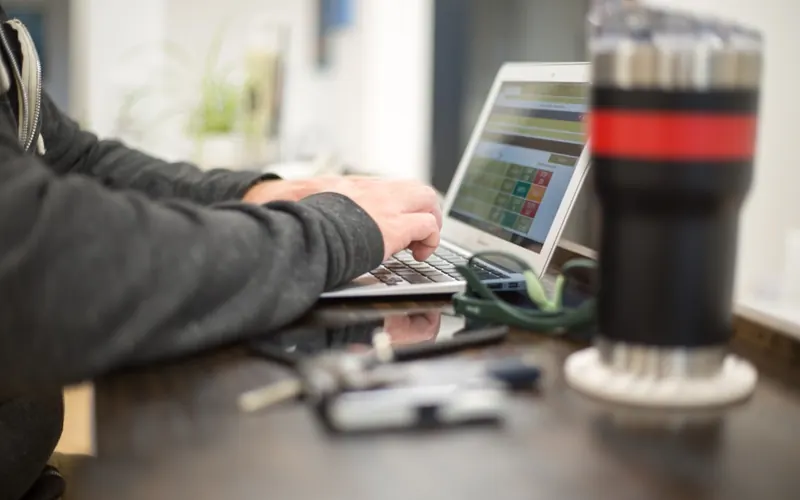 Homem com celular e notebook no escritório
